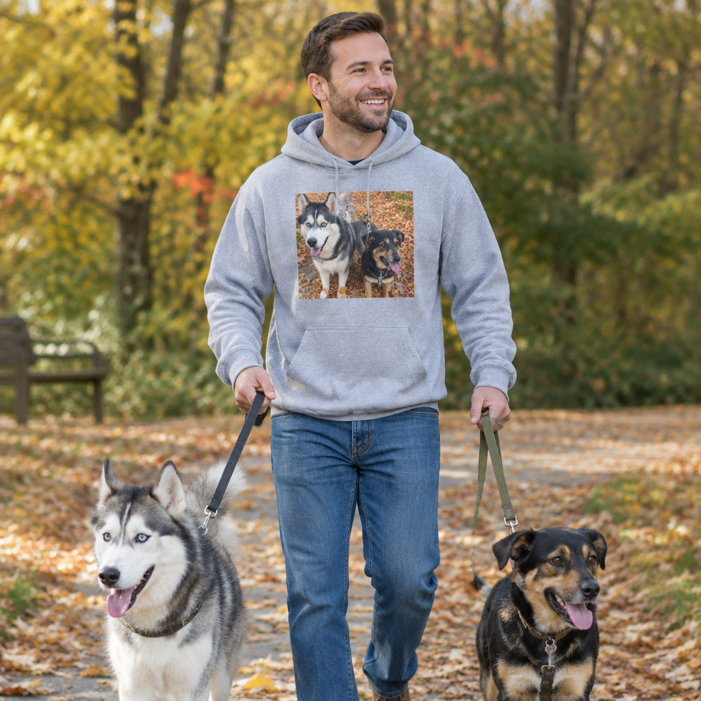 Man in a grey photo hoodie walking his two dogs